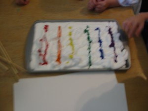 Marble painting step 1: Shaving cream on a baking pan with a tempera rainbow. 